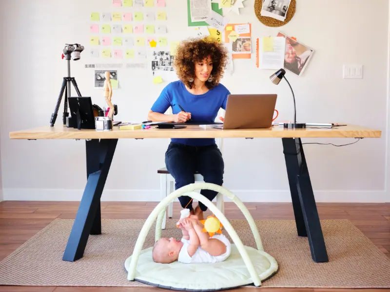 Work-Life-Balance im Homeoffice. Frau arbeitet am Laptop und kümmert sich um ihr Baby